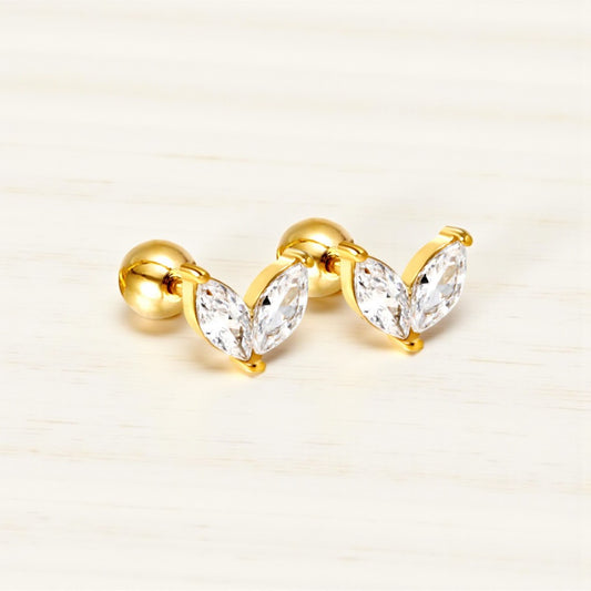 Gold earrings with clear gemstones on a beige background