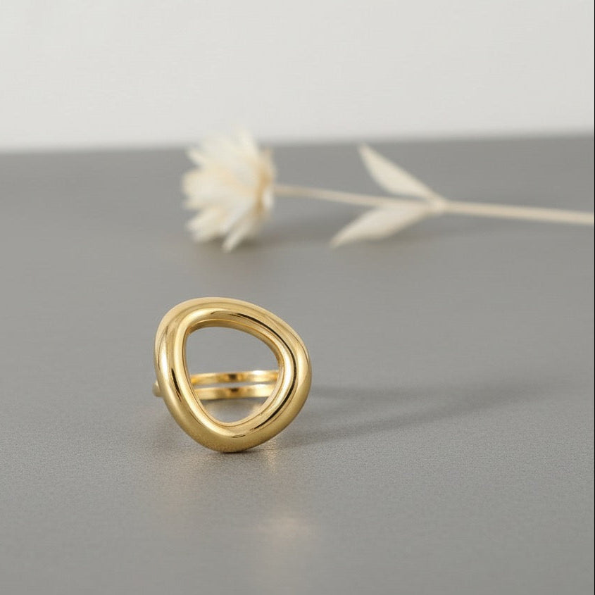 Gold ring on a gray surface with a white flower in the background