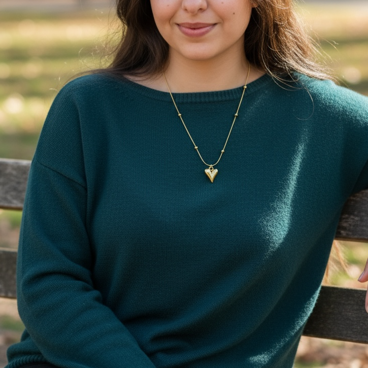 Woman in a teal sweater sitting on a bench in a park with trees and grass in the background.