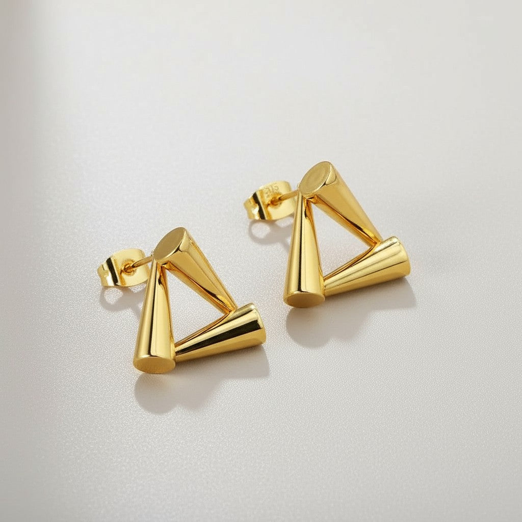 Gold triangle-shaped earrings on a light gray background