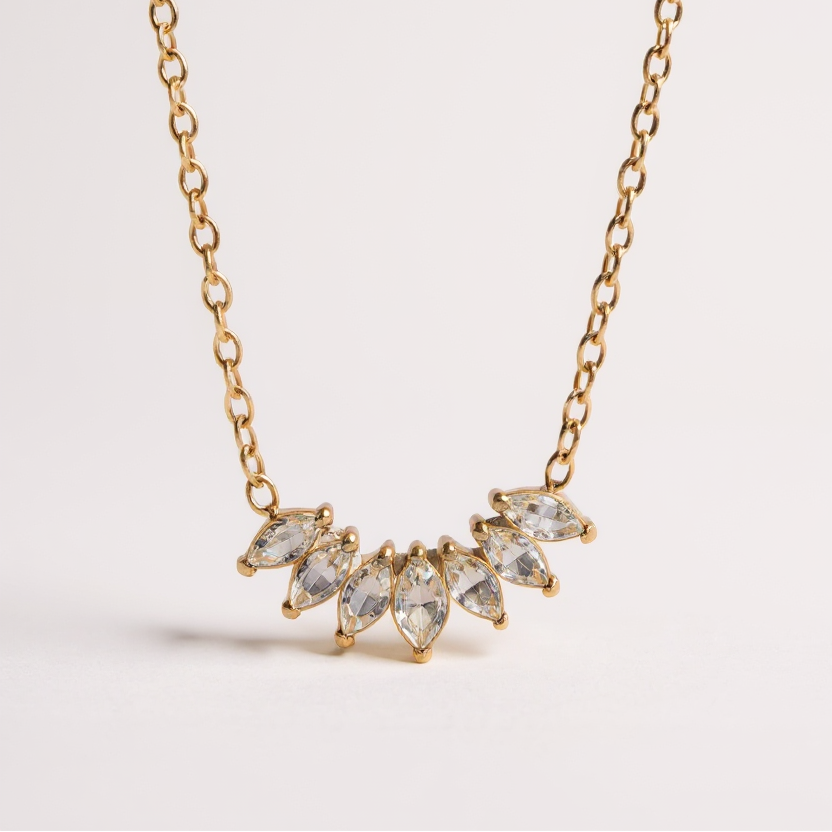 Gold necklace with clear gemstones on a light gray background