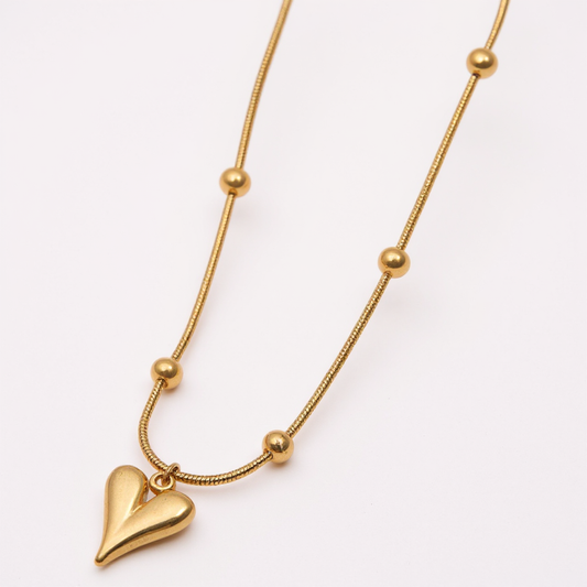 Gold necklace with a heart pendant on a white background